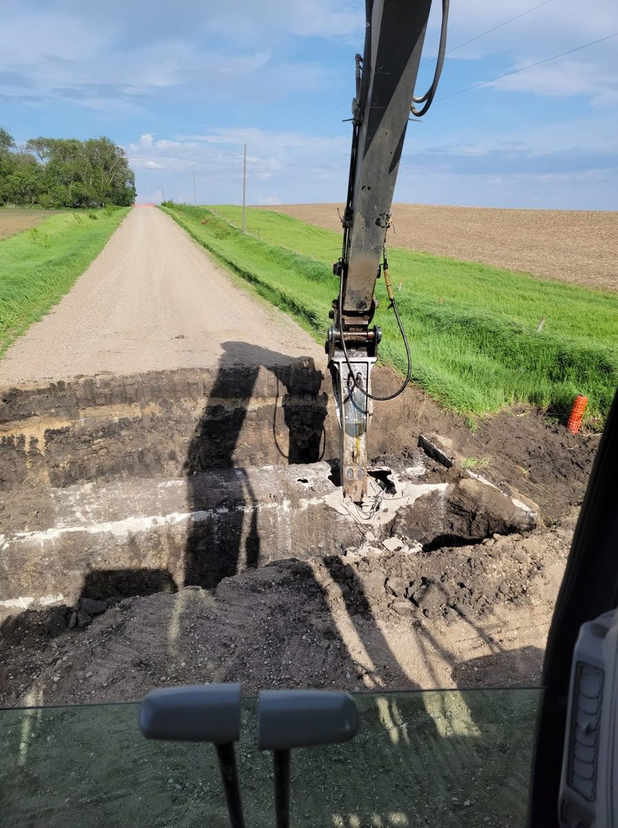 Excavator removing an old culvert along a field road near Storm Lake, Iowa